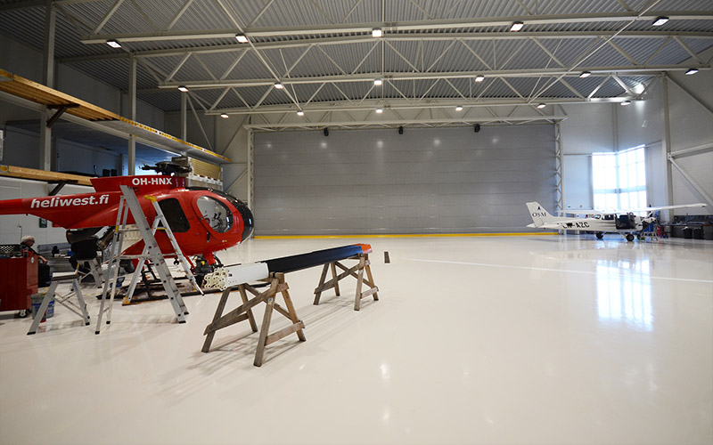 ERE hangar interior med ett rødt helikopter og ett hvitt småfly.